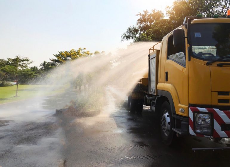 A Yellow Truck Spraying Water to the Ground — Spray Grass in Northern Territory