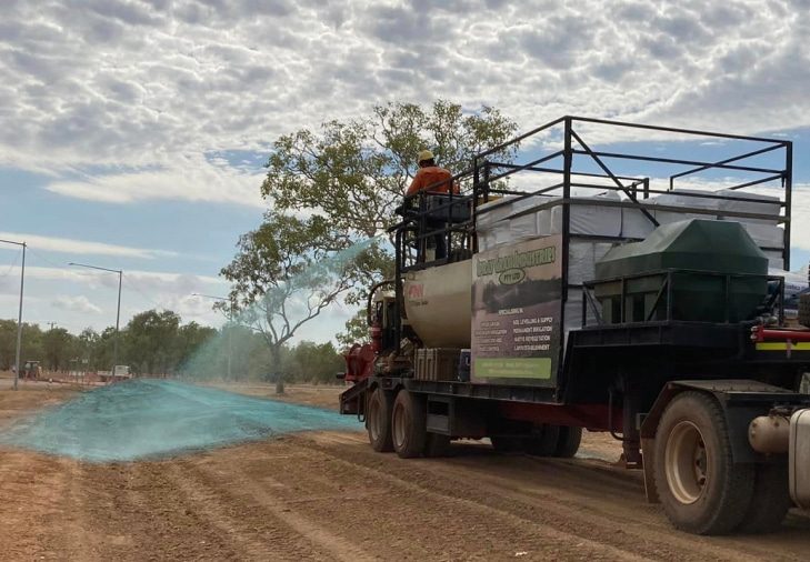 A Man in Orange Suit Spraying Flexterra on the Soil — Spray Grass in Northern Territory
