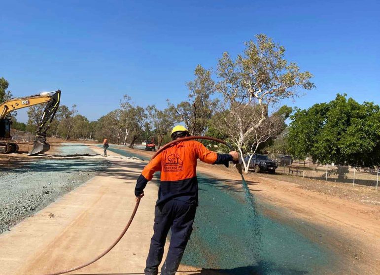 A Man in Orange Suit Spraying Flexterra on a Wide Ground — Spray Grass in Northern Territory